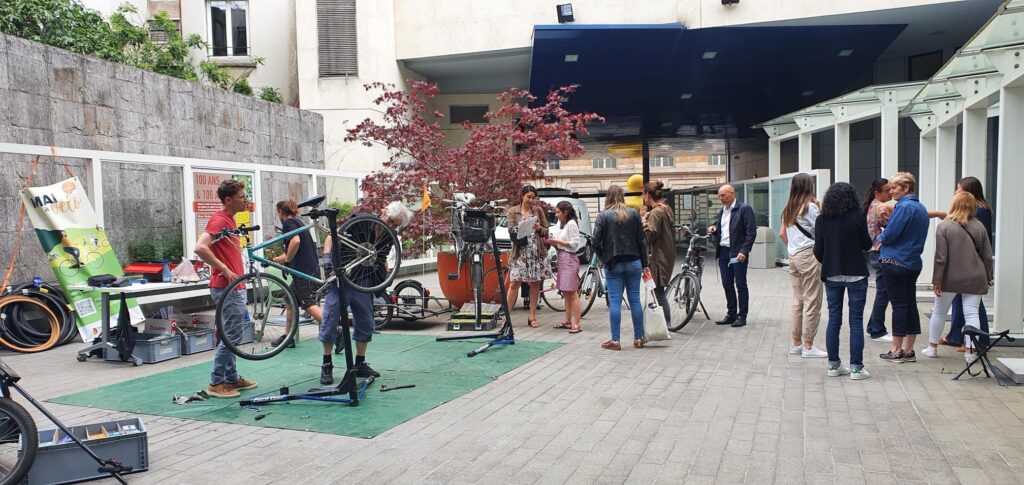 Photo d'une animation de réparation de vélo en entreprise avec une dizaine de participants et deux mécaniciens au travail.