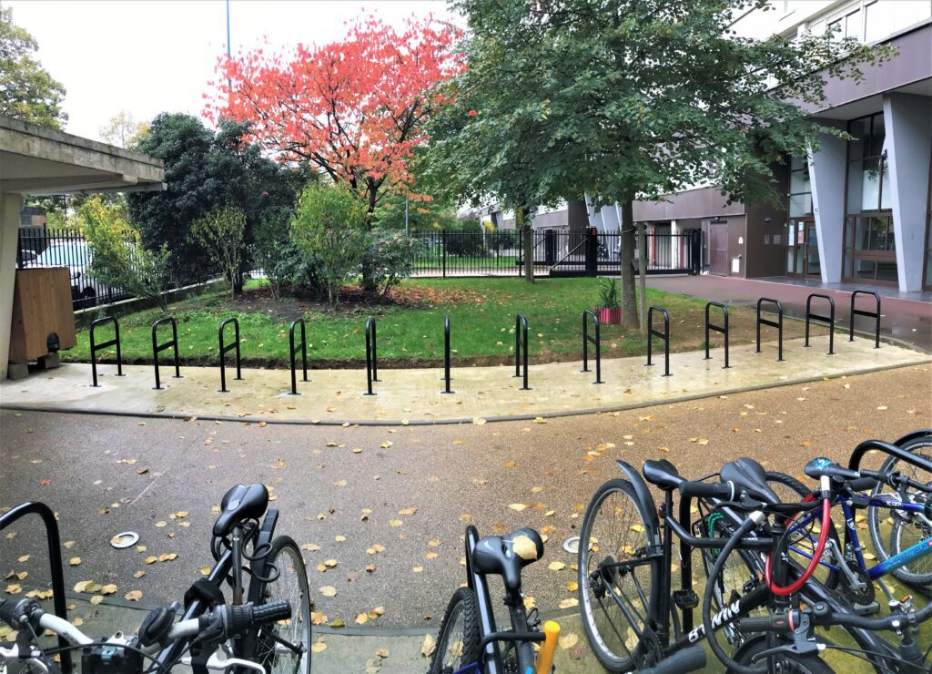 Photo de deux rangées de 13 arceaux de stationnement vélo le long d'une allée en extérieur.