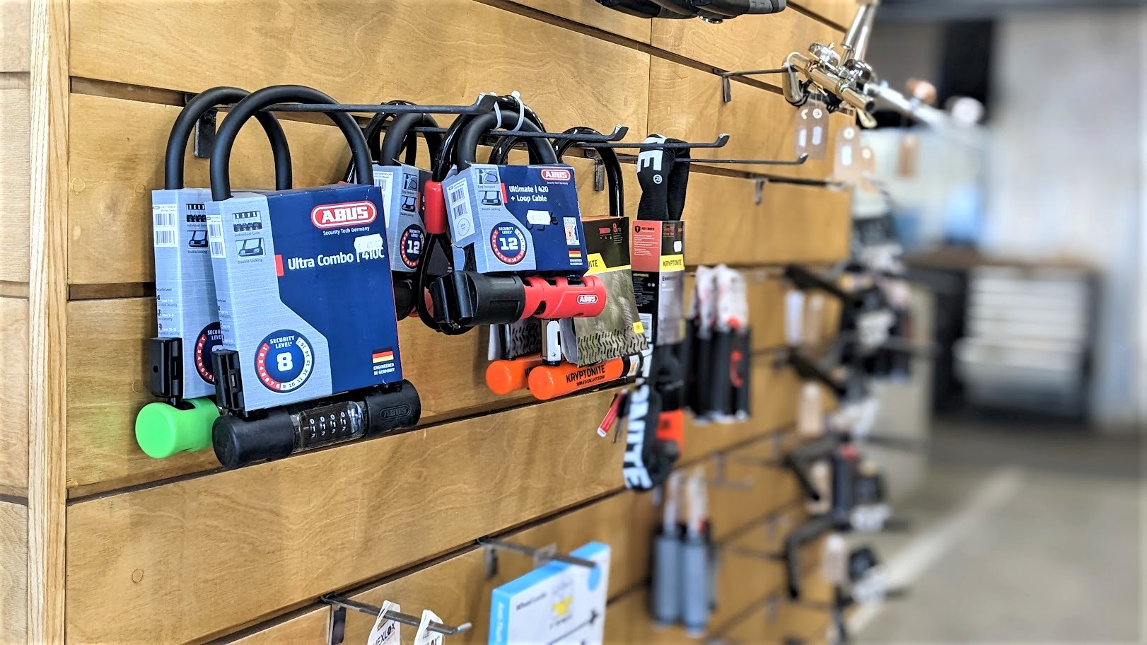 Photo d'une sélection d'antivols de vélo sur un mur en bois dans la boutique de La Fabrique des Cyclistes.