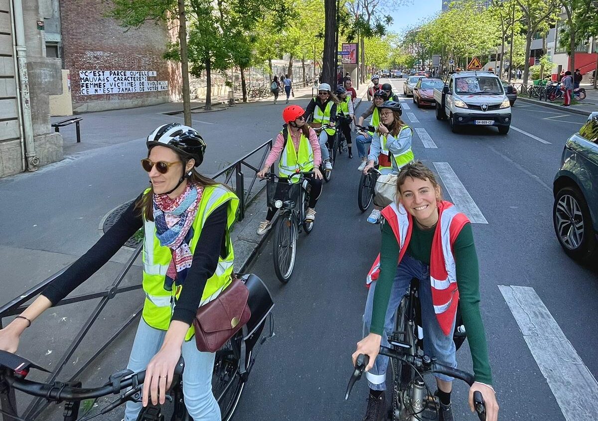 Photo d'un groupe de personnes à vélo, arrêtées en deux files sur une large piste cyclable à Paris.