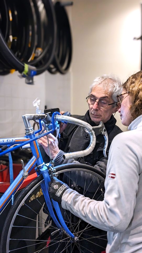 Photo d'une mécanicienne et d'un mécanicien de La Fabrique des Cyclistes travaillant ensemble sur un vélo vintage.