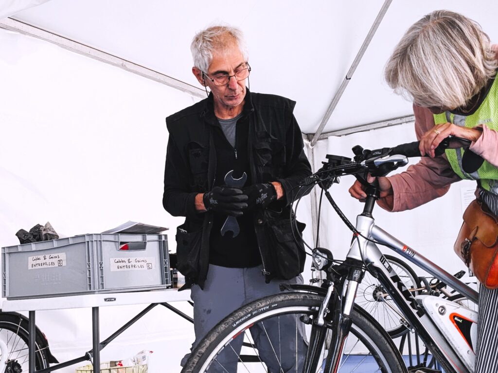 Photo d'un mécanicien de La Fabrique des Cyclistes supervisant la réparation effectuée par une participante lors d'un atelier d'autoréparation.