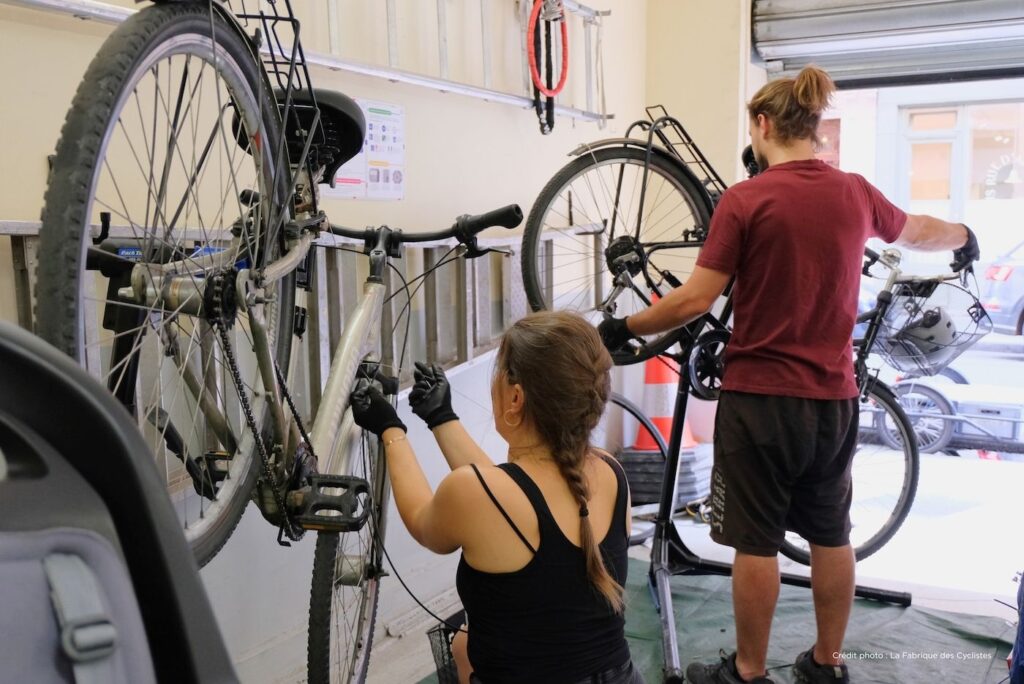 Photo d'une mécanicienne entrain de réparer un vélo dans le garage d'une entreprise lors d'un atelier mobile.